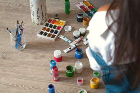 Set of watercolor paints, gouache, paint brushes on the floor. Artist's workshop in the process of...