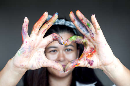 Happy woman hiding the face with her painted hands and fingers. Creative, art, drawing conceptの写真素材