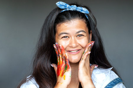 Happy woman hiding the face with her painted hands and fingers. Creative, art, drawing conceptの写真素材