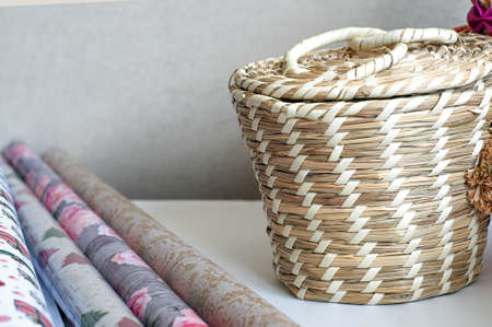 colorful wrapping paper rolls with wicker basket with decor on tableの写真素材