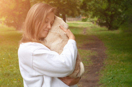 Lifestyle of cute young woman holding pug dog and smiling. Loving dog in his owner's arms in the...