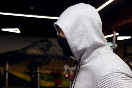 Young athletic man wearing protective face mask while having sports training in a gym during coronavirus epidemic.の写真素材