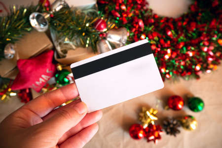 Man hands holding credit card by festive xmas presents and decor - close up. christmas online shoppingの写真素材