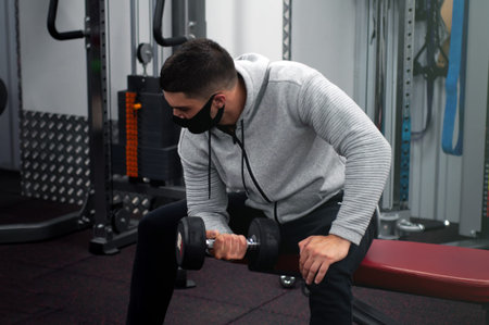 power athlete sportsman bodybuilder , execute exercise with dumbbells, in dark gym, sportsman...