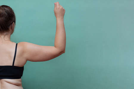 Conscious young woman holding excess fat on her arm against, Close up with copy spaceの写真素材