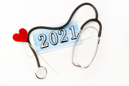 Stethoscope with 2021 number and medical mask with heart on white background. Happy New Year for health care. Top view.の写真素材