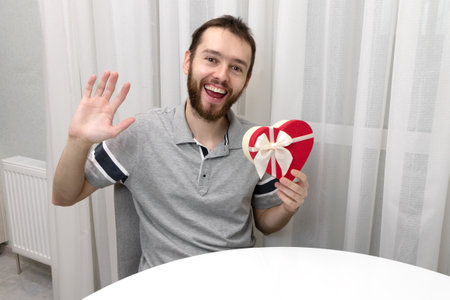 Man with gift and laptop. Valentines Day online holiday remote celebration lockdown coronavirus quarantine covid 19, social distance, remote communication, stay home vocation, party online virtualの写真素材