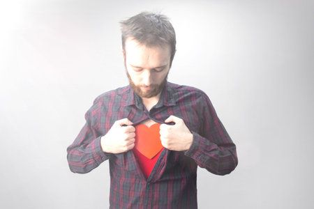 A man opening his shirt with a red heart on his chest. Saint valentine day conceptの写真素材