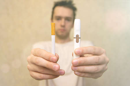 In hand choosing between tobacco modern hybrid electronic cigarette device with heating system or classic cigarette. Health safety alternative, set e-cigarette vs nicotineの写真素材