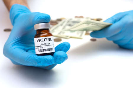 Coronavirus vaccine cost. vaccine ampoule in hand and money. Fight against Covid-19. Pevention, immunization and treatment conceptの写真素材