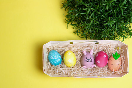 Close up of colored painted easter eggs lie in the hay on a white tray. Stylish modern rustic easter...