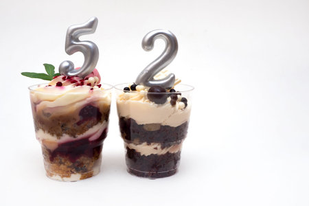 Birthday trifle cake with candle labeled number 52 on white background with copy space. portioned...