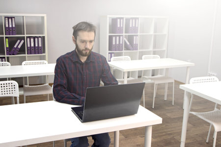 Young man alone working on computer in modern office. Working in social distancing situation