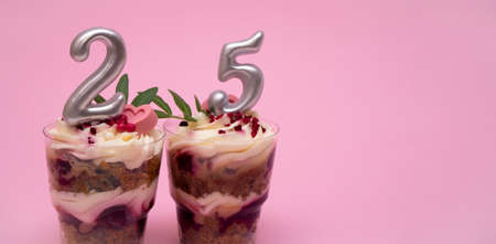 Birthday trifle cake with candle labeled number 25 on pink background with copy space. portioned mini cakeの写真素材