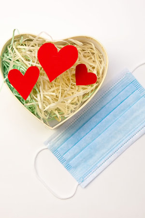 New normal valentines day congratulation concept. Valentine day amid the covid-19 pandemic. Heart shape gift box with bow and face mask.の写真素材