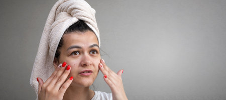 woman applying face cream on her face. Spa and wellness at home. Skin Care facial Concept. Banner with copy spaceの写真素材