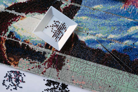 Diamond mosaic with crystals and tweezers close up. relaxation and rest from work in the process of monotonous activitiesの写真素材