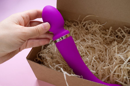 Sex toy pink vibrator in craft box. Online shopping and delivery, close up.
