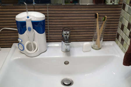 Tools for cleaning teeth on sink. Irrigator and dental floss with bamboo eco toothbrushes. Zero waste, sustainable bathroom and lifestyleの写真素材