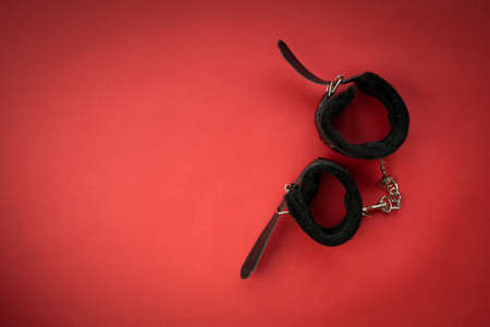 BDSM black leather handcuffs on red background. Sex toys with copy spaceの写真素材