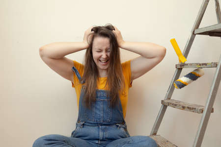 Tired exhausted frustrated stressed woman doing a home renovation. difficulties and problems panic a young girlの写真素材