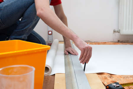 Man repair measures the length of the strip of wallpaper. renovation apartmentの写真素材