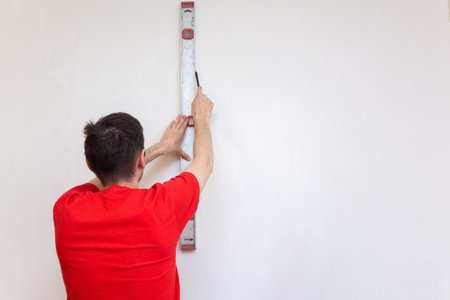 Man repair worker checking level of the wall with the bubble level tool. Renovation apartment...