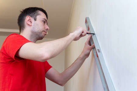 Man repair worker checking level of the wall with the bubble level tool. Renovation apartment...