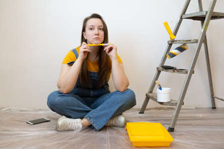Independent young woman planning renovation apartment sitting on floor with construction tool. diy repair owner handsの写真素材