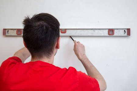 Man repair worker checking level of the wall with the bubble level tool. Renovation apartment...