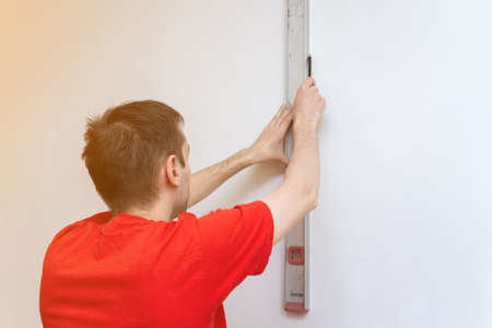 Man repair worker checking level of the wall with the bubble level tool. Renovation apartment...