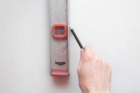 Man repair worker checking level of the wall with the bubble level tool. Renovation apartment...