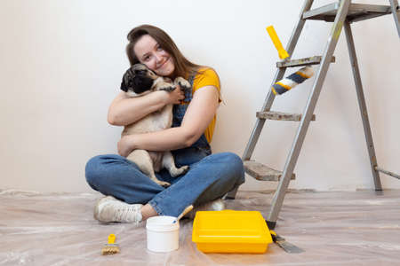 woman hugs pet dog in her new house during renovation, construction tools and ladder on the background. Independent single female life with petの写真素材