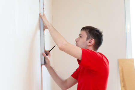 Man repair worker checking level of the wall with the bubble level tool. Renovation apartment...