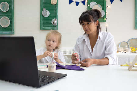 Mom and daughter are engaged in pottery online class by video lesson by ceramic art studio. video master class on creating ceramic products.の写真素材