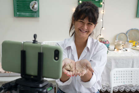 Woman pottery tutor in art studio record video lesson for ceramict online course or leads a video...