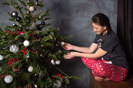 Woman in pajamas near Christmas tree and gifts. Dark blue conceptの写真素材