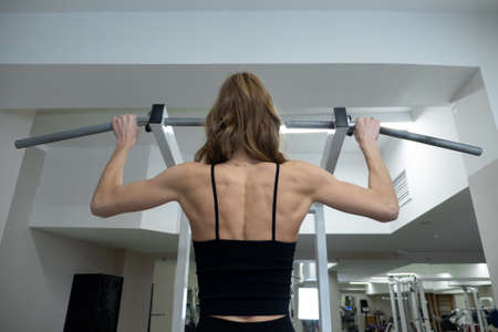 Fitness sporty woman in training pumping up muscles of the back and hands. Close up of female...