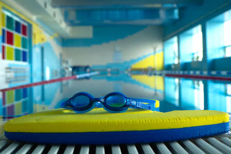 Swim board with Goggles on beside of the swimming pool in sports center. swimming training concept....