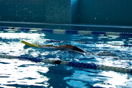 unrecognizable kid swimming freestyle style training in swimmer pool with splashing waterの写真素材