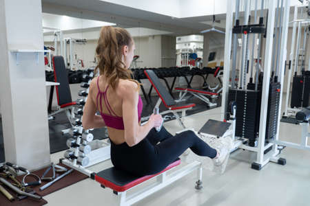 Confident young sportswoman exercising on a rowing machine at the gym. Concept of a healthy sport...