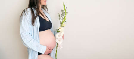 Side view authentic relax pregnant woman with flower in shirt with big bare tummy. healthy...