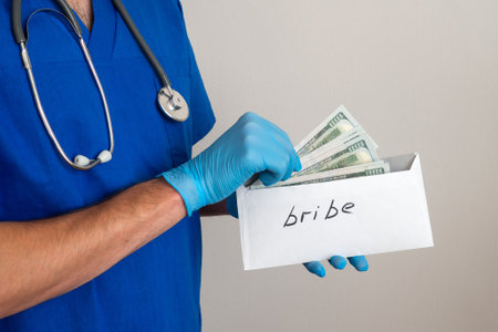 Male medicine doctor holding in hands bunch of hundred dollars banknotes counting them. Concept of corruption in healthcare. Bribe to the doctorの写真素材