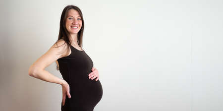 Side view elegant pregnant woman in dress with belly in hands. healthy pregnancy concept. Banner copyspace for text.の写真素材