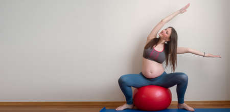 Healthy fitness pregnant woman doing yoga workout on yoga mat. healthy and active pregnancy concept. banner with copy space for textの写真素材