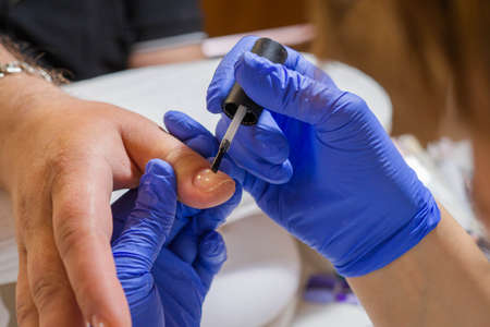manicure master paints the man clients nails with gel polish in a beauty salon. Manicure male...