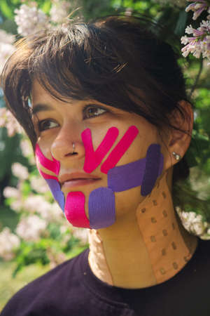 Physiotherapy of Face aesthetic taping. Portrait of woman with pasted konesiotape for rejuvenation and face tightening without surgery. Anti-wrinkle cosmetic tape.の写真素材