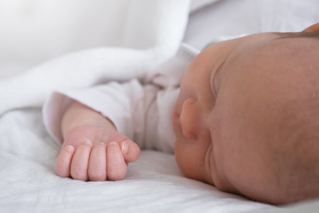 cute little newborn baby girl peacefully sleeps in the nursery on a white cotton bed. selective focusの写真素材