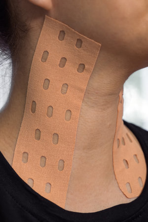 Physiotherapy of neck aesthetic taping. Portrait of woman with pasted konesiotape for rejuvenation...