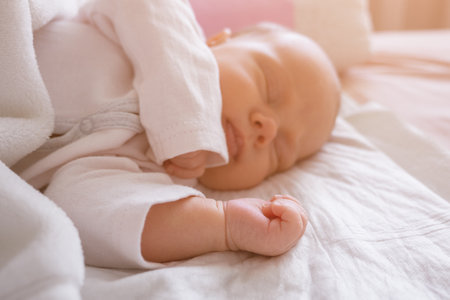 cute little newborn baby girl peacefully sleeps in the nursery on a white cotton bed. selective focusの写真素材
